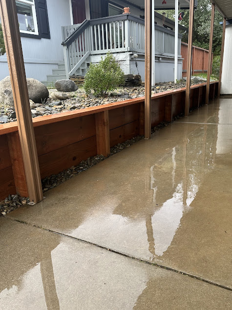 A concrete patio with a wooden fence and a house in the background.