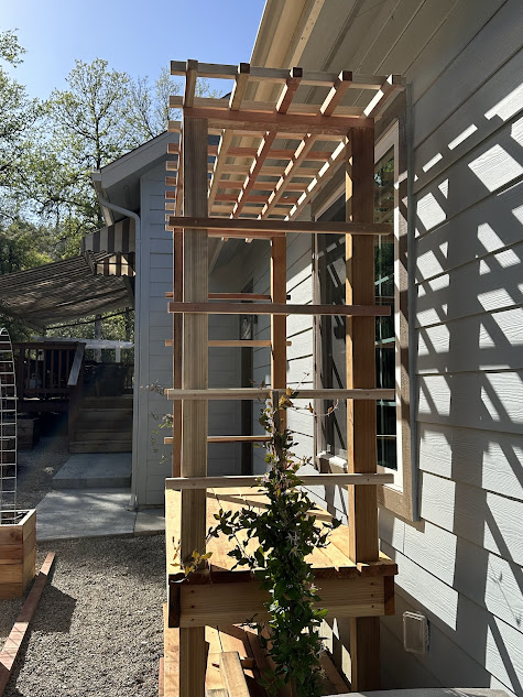 A wooden pergola is being built on the side of a house.