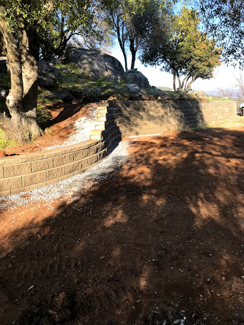 There is a brick wall in the middle of a dirt field.