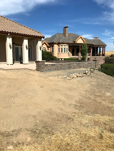 A large house is sitting on top of a dirt hill.