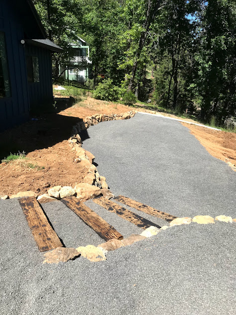 A driveway with stairs leading up to a house in the woods.