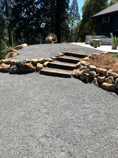A gravel driveway with stairs leading up to a house