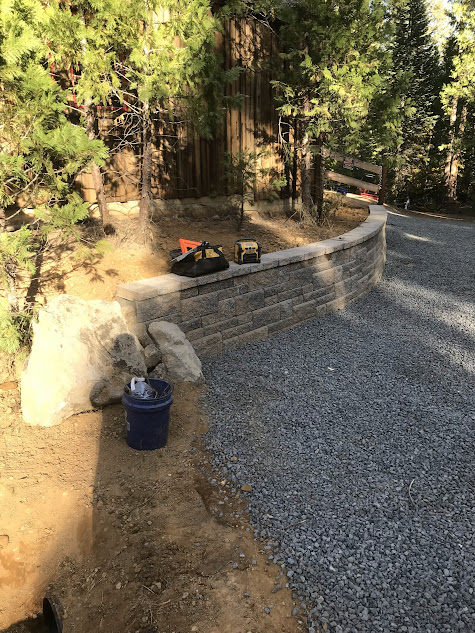 A blue bucket is sitting on the ground next to a brick wall.