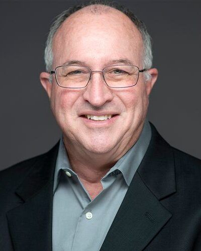 Agent John Martin with glasses in black blazer and gray shirt.