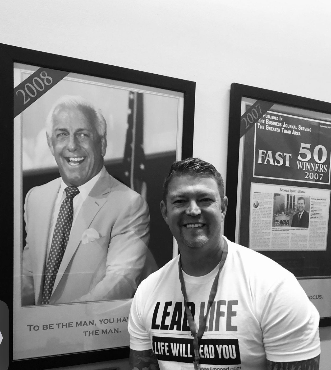 Man smiles in front of framed images of Ric Flair and a 