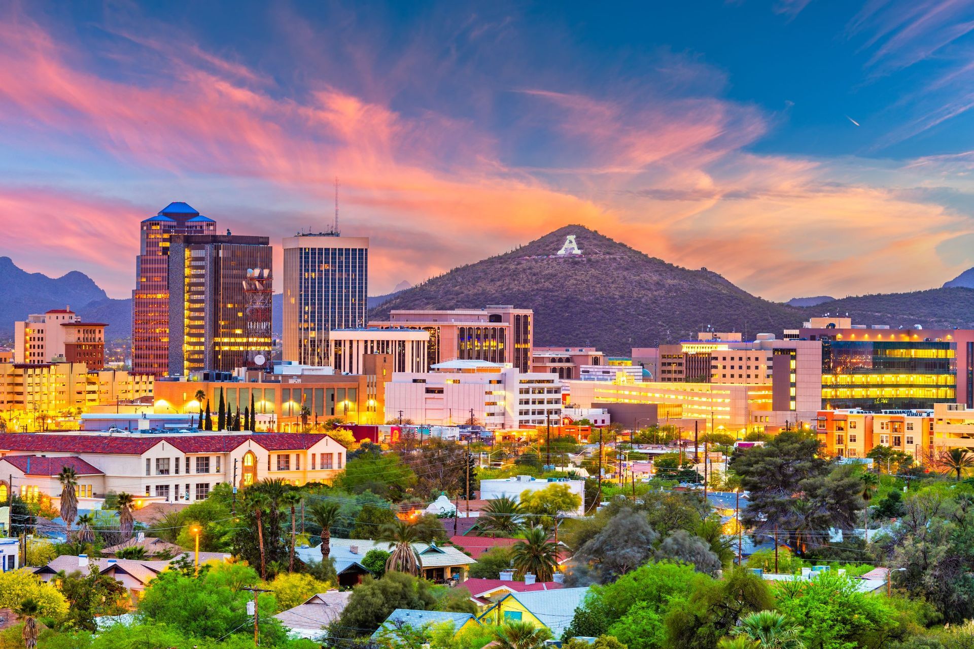 Downtown Tucson skyline at sunset with colorful sky and Santa Catalina Mountains.