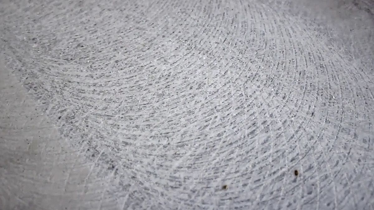 Close-up of a gray, textured surface with overlapping, white scratch marks.