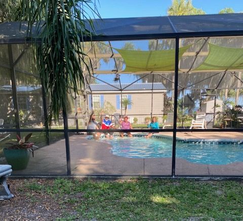 A screened in pool with people swimming in it.