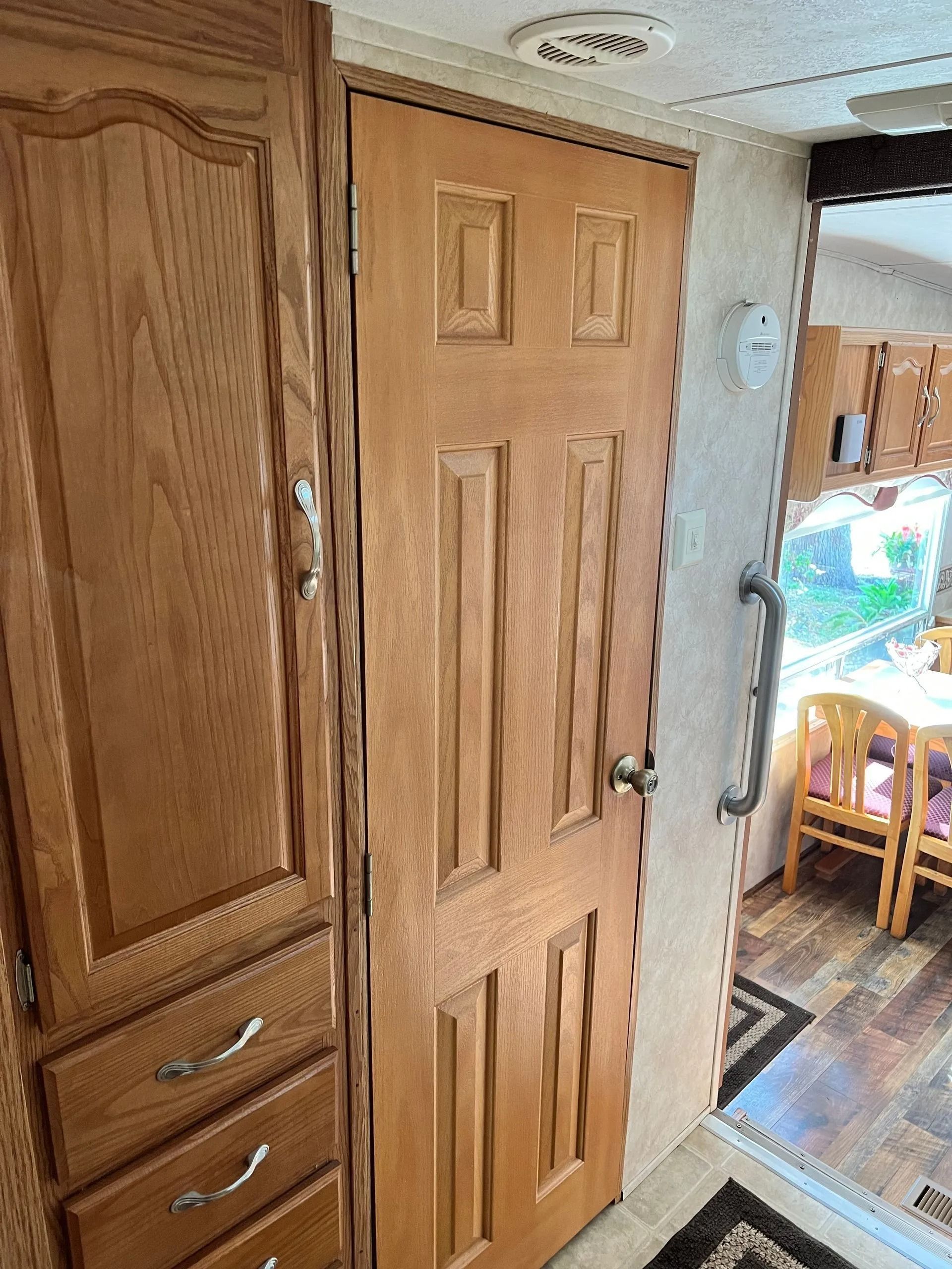 A wooden door is between two cabinets in a room.