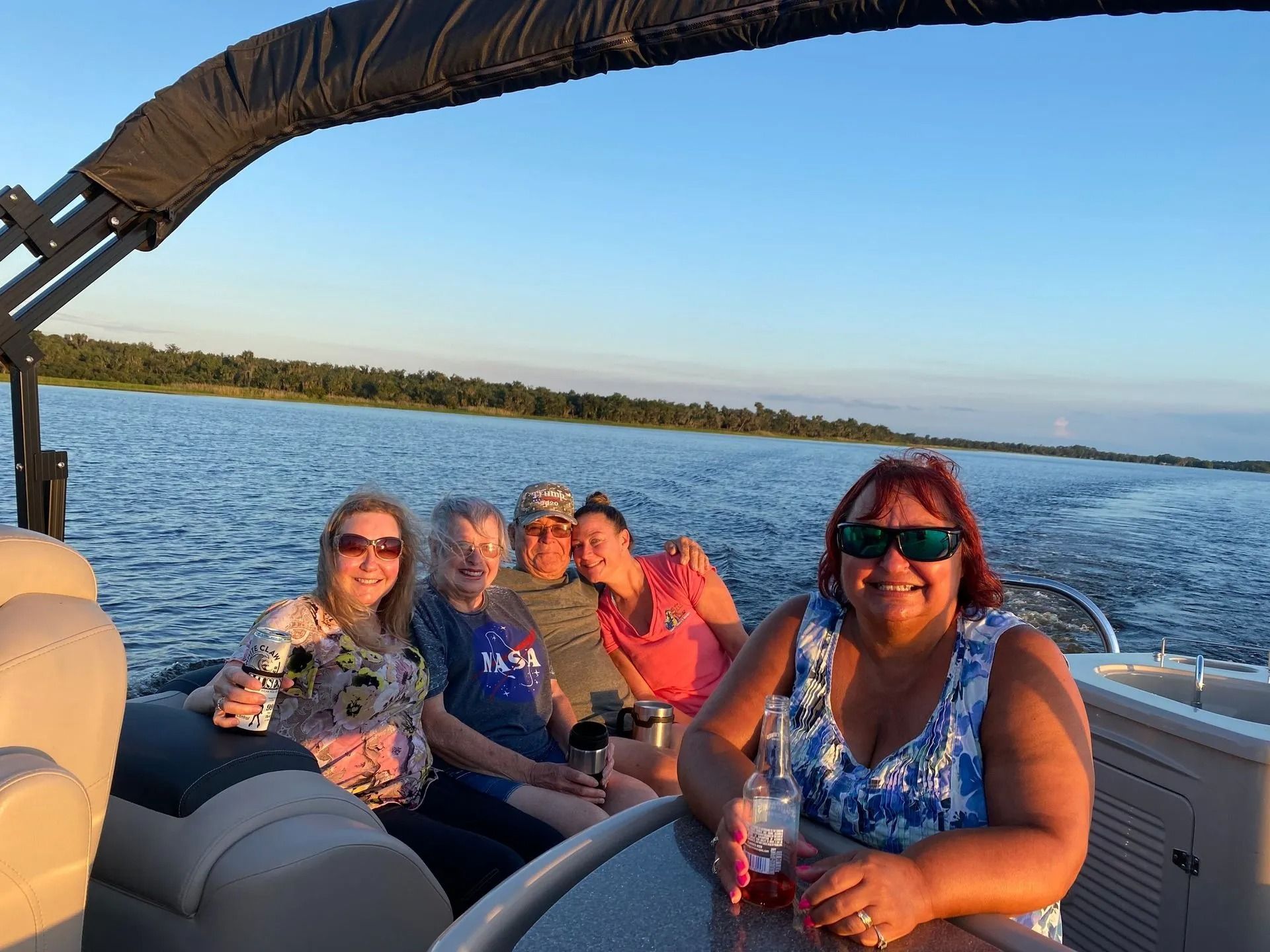 A group of people are sitting on a pontoon boat on a lake.
