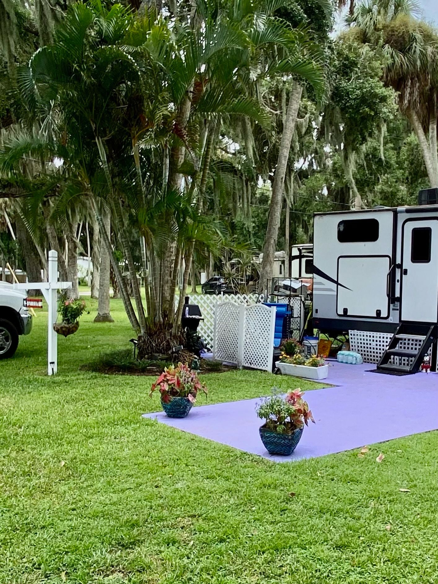 A rv is parked in a grassy field next to a truck.
