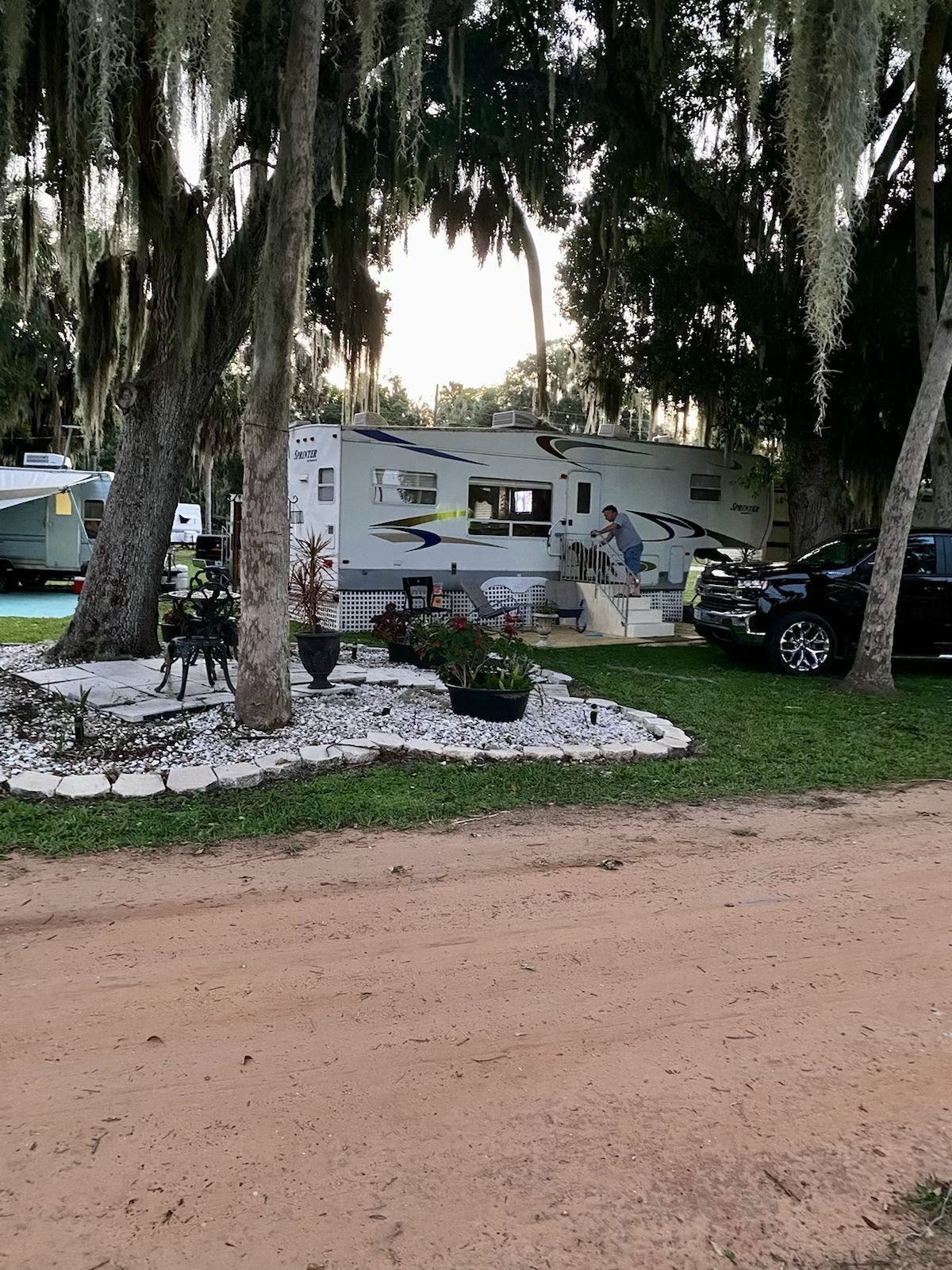A rv is parked in a grassy area next to a dirt road.