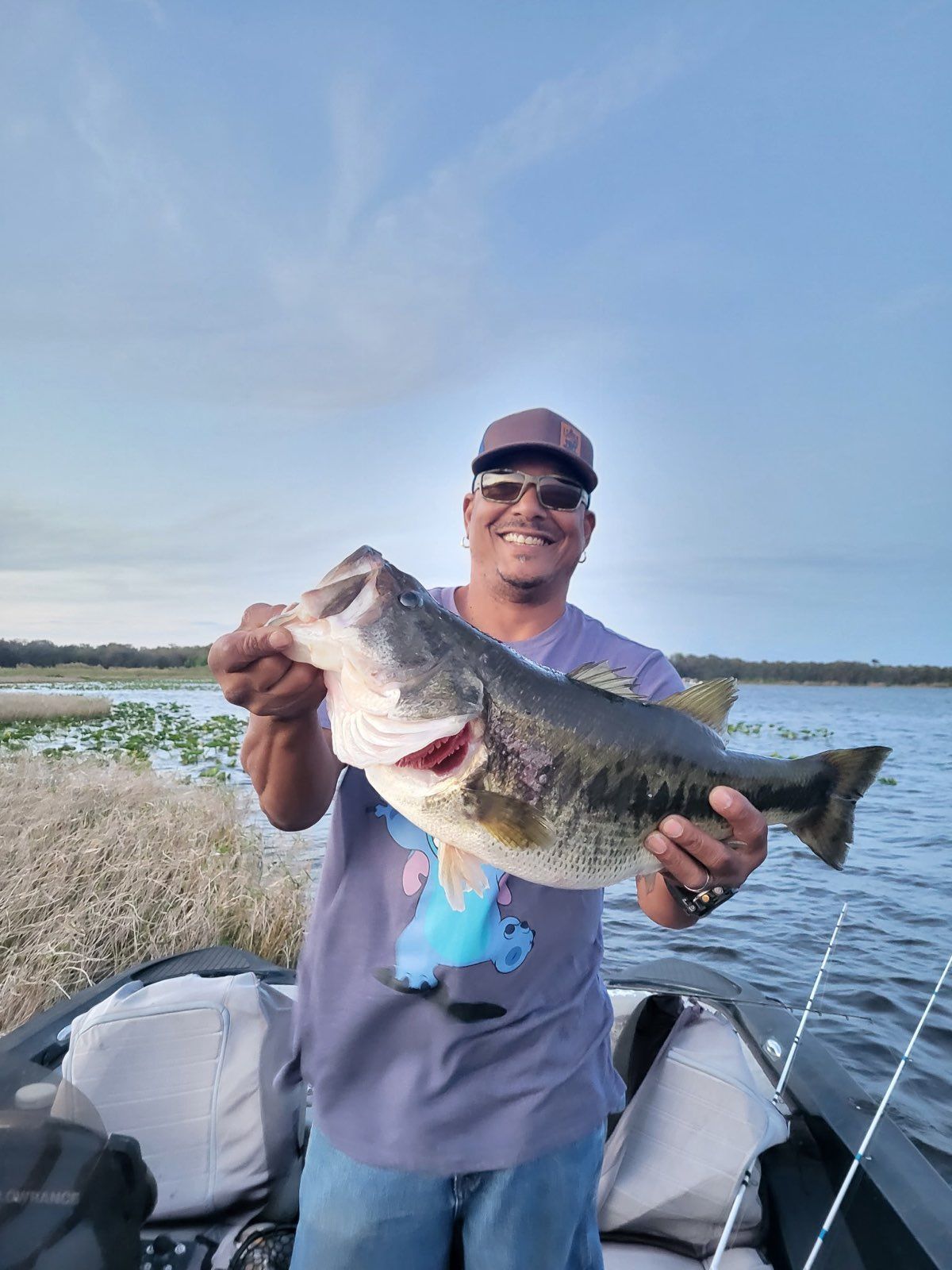 A man is holding a large bass on a boat.