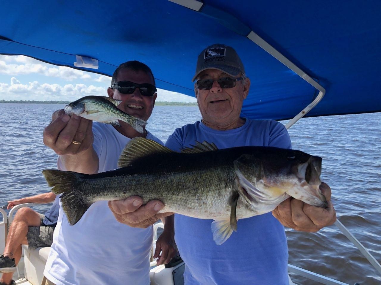 Two men are holding fish in their hands on a boat.