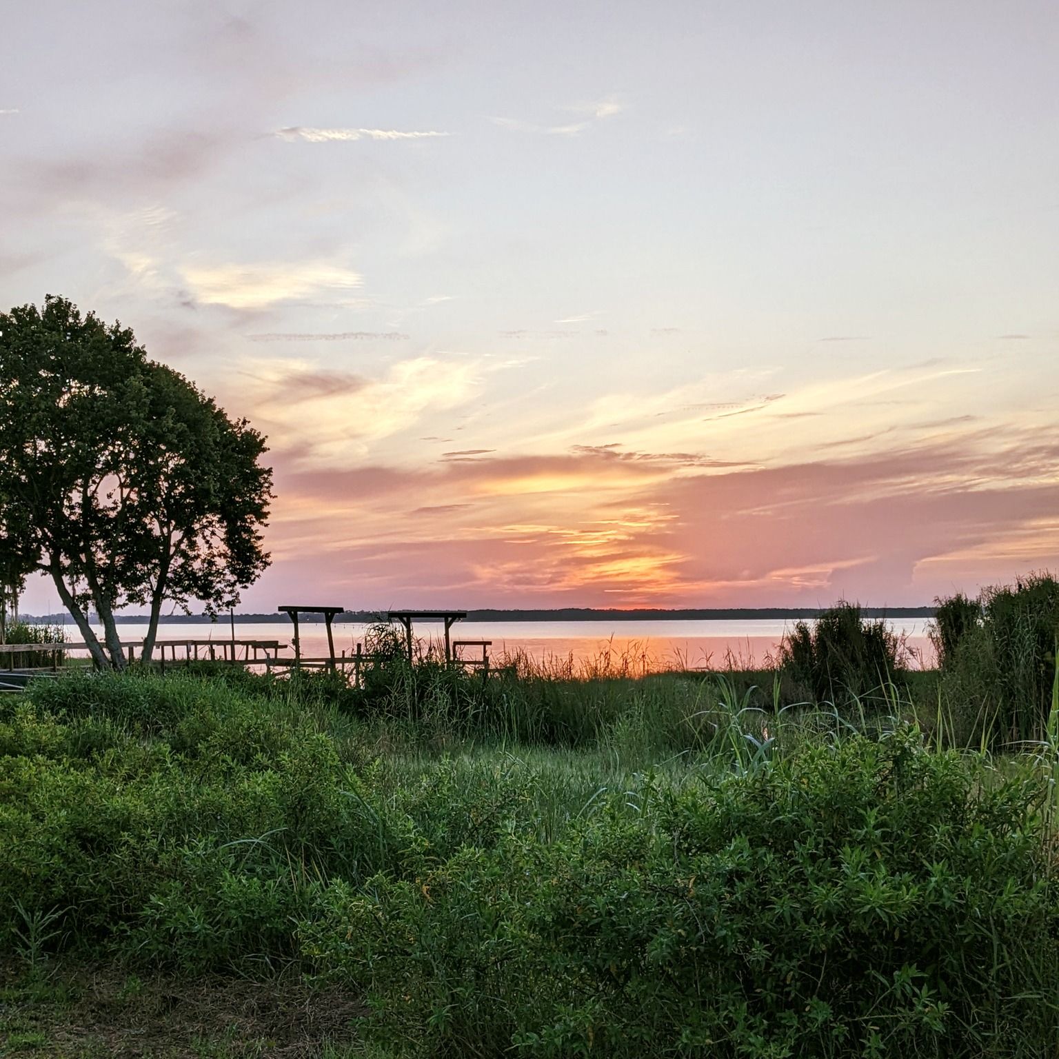 A sunset over a lake with a picnic table in the foreground.
