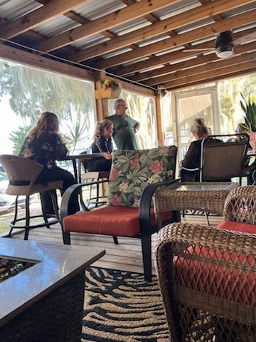A group of people are sitting at tables on a porch.