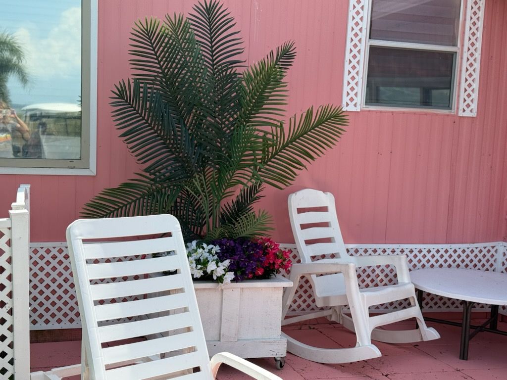 Two white rocking chairs are in front of a pink house