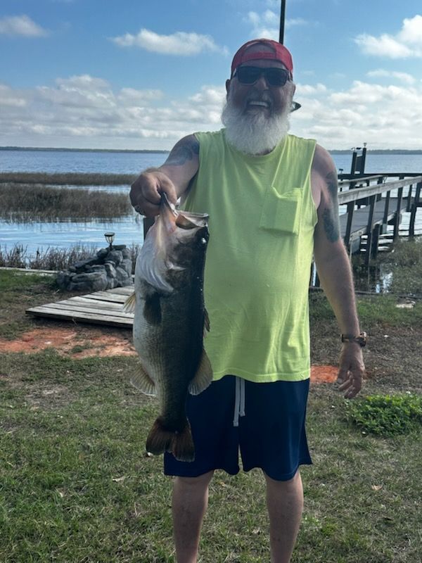 A man in a yellow tank top is holding a large fish