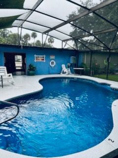 A large swimming pool is surrounded by a screened in area.
