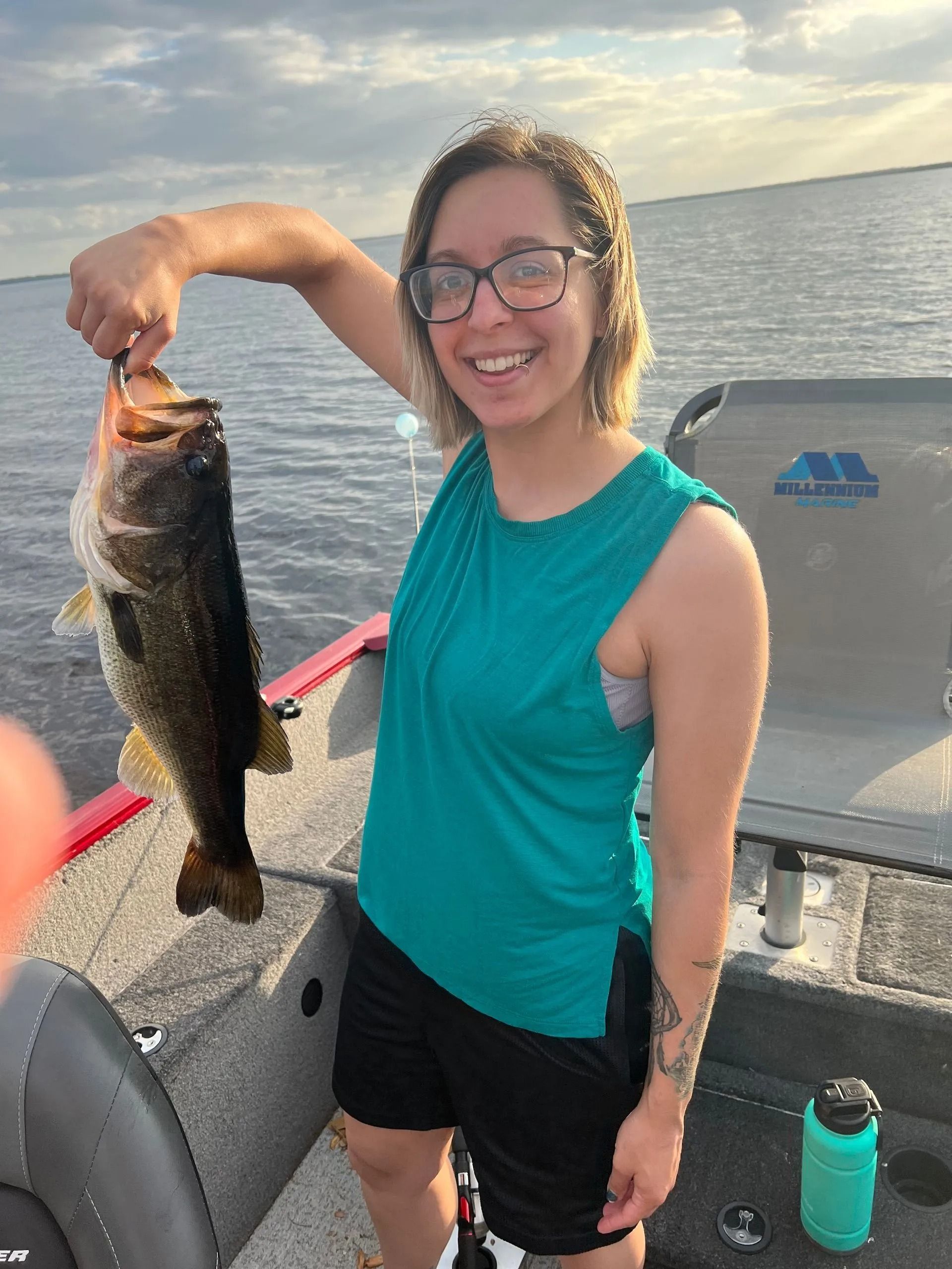 A woman is holding a fish in her hand on a boat.