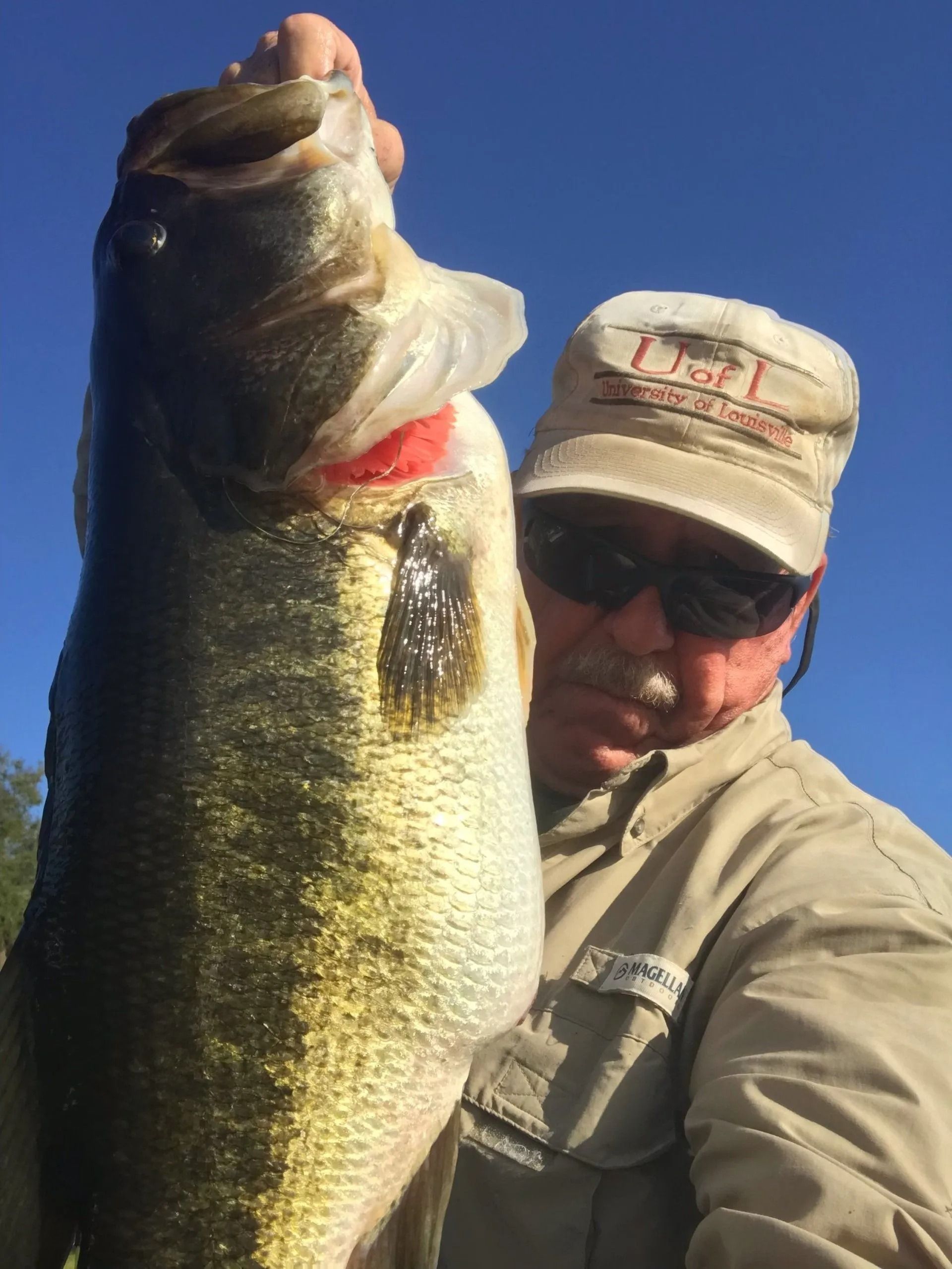 A man in a hat is holding a large fish.
