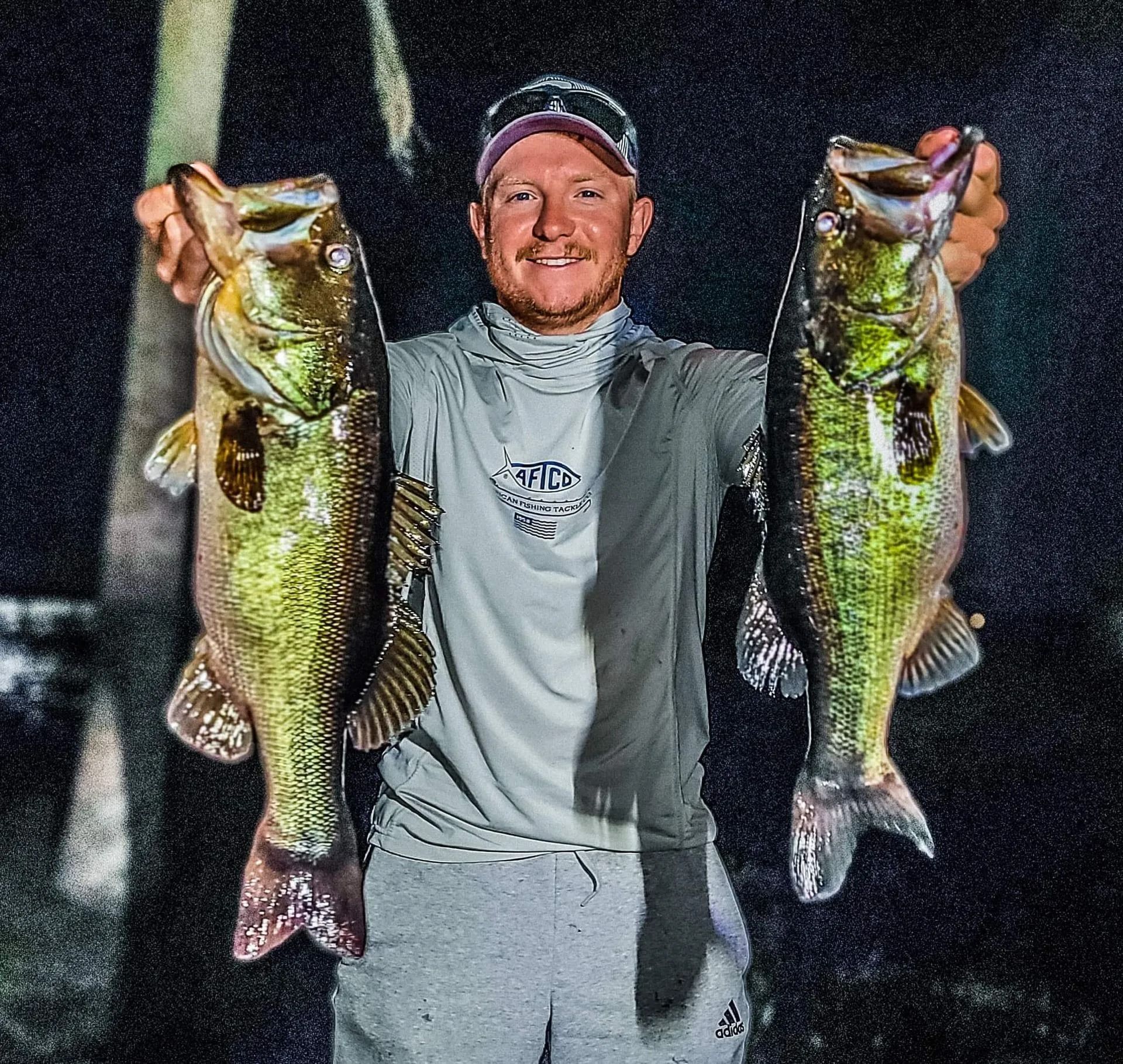 A man is holding two large fish in his hands