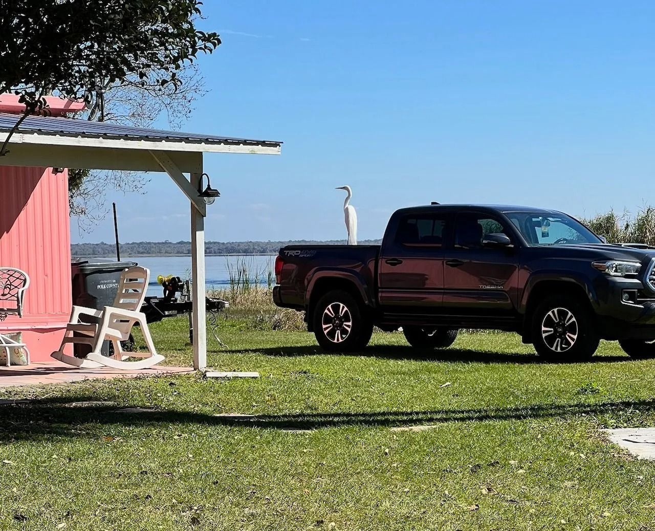 A truck is parked in the grass in front of a pink building.