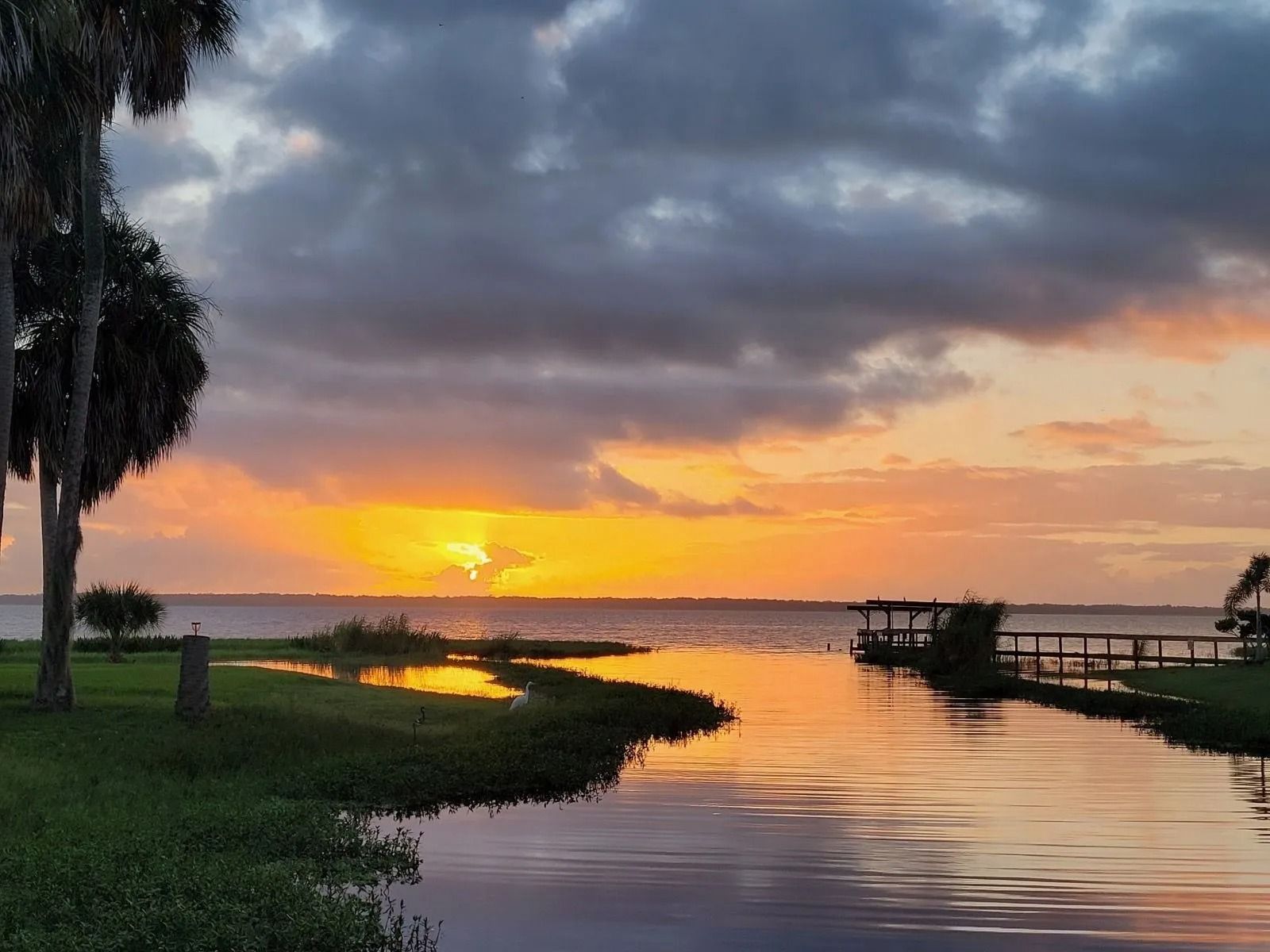 A sunset over a body of water with trees in the foreground