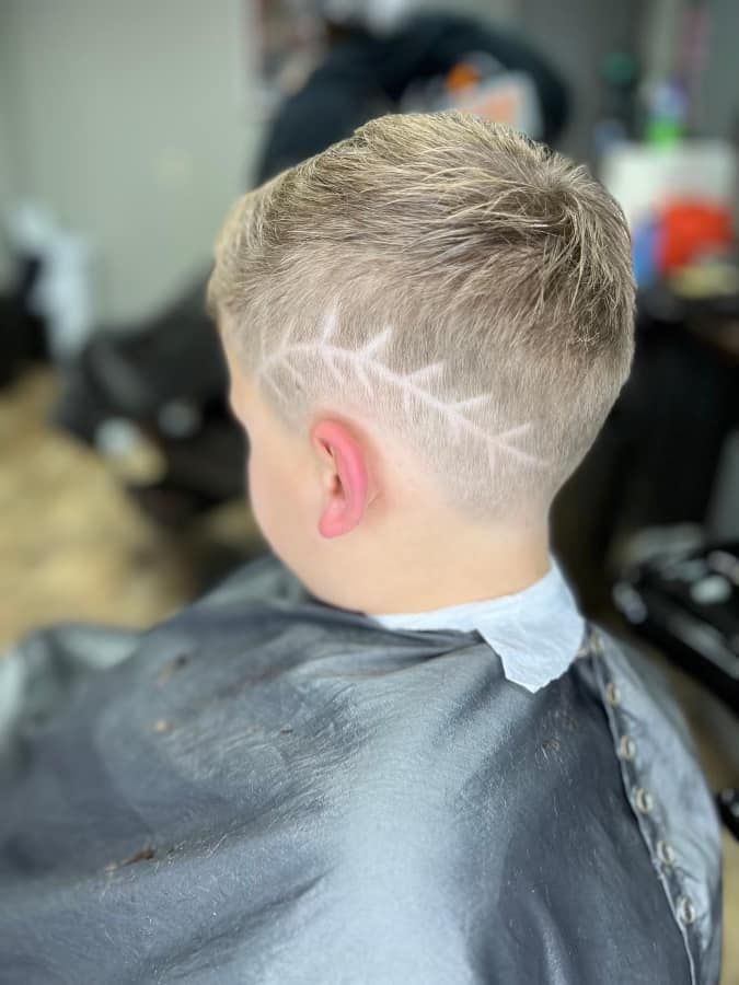 Child with blond hair getting a fresh side haircut in a barbershop chair
