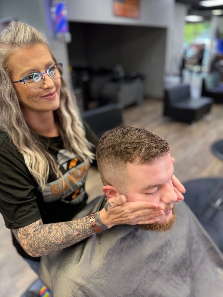 Person getting a straight razor shave at a barbershop. Barber shaves the man's beard while he reclines.