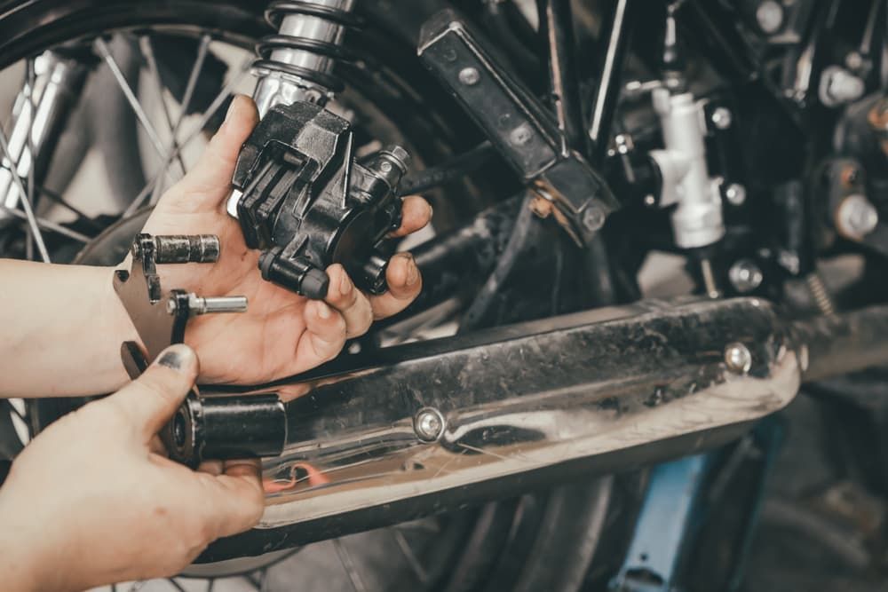 A Person Is Working On A Motorcycle In A Garage — Shamrock Mower & Motorcycle Repairs in Braemar, NSW