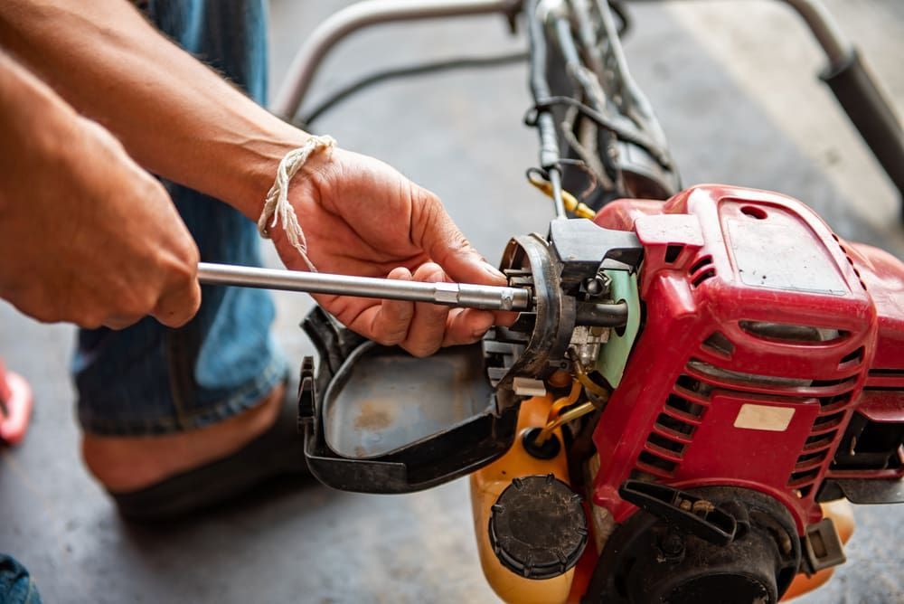 A Person Is Fixing A Lawn Mower With A Wrench  — Shamrock Mower & Motorcycle Repairs in Braemar, NSW