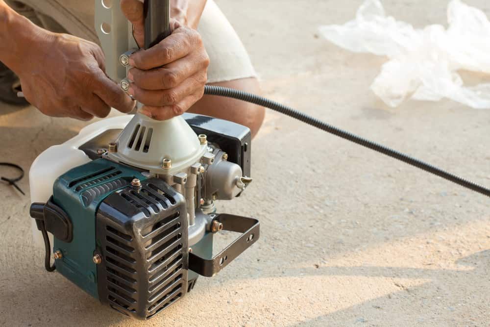 A Man Is Fixing A Lawn Mower On The Ground — Shamrock Mower & Motorcycle Repairs in Braemar, NSW