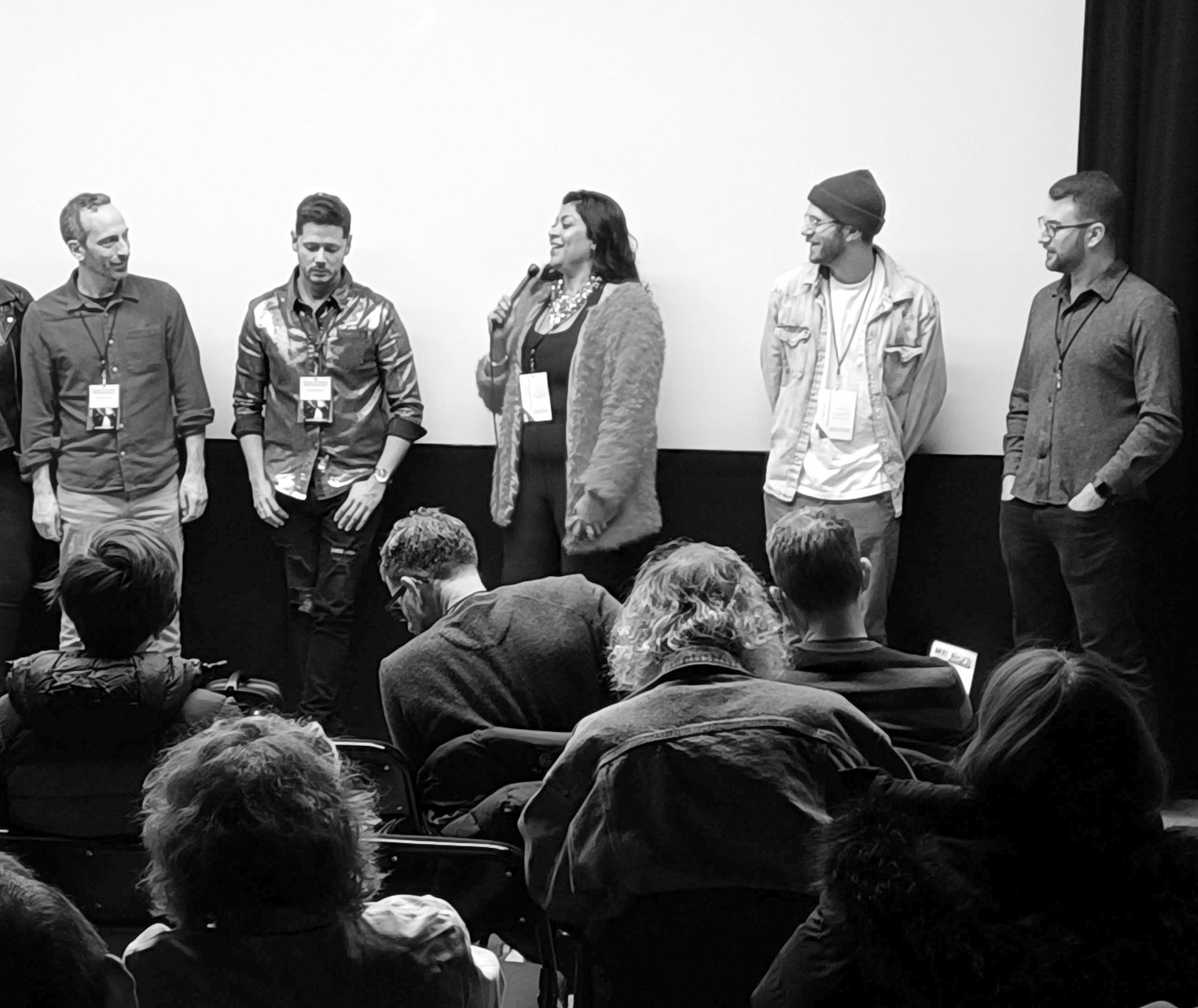 A group of people are standing in front of a screen in a black and white photo.