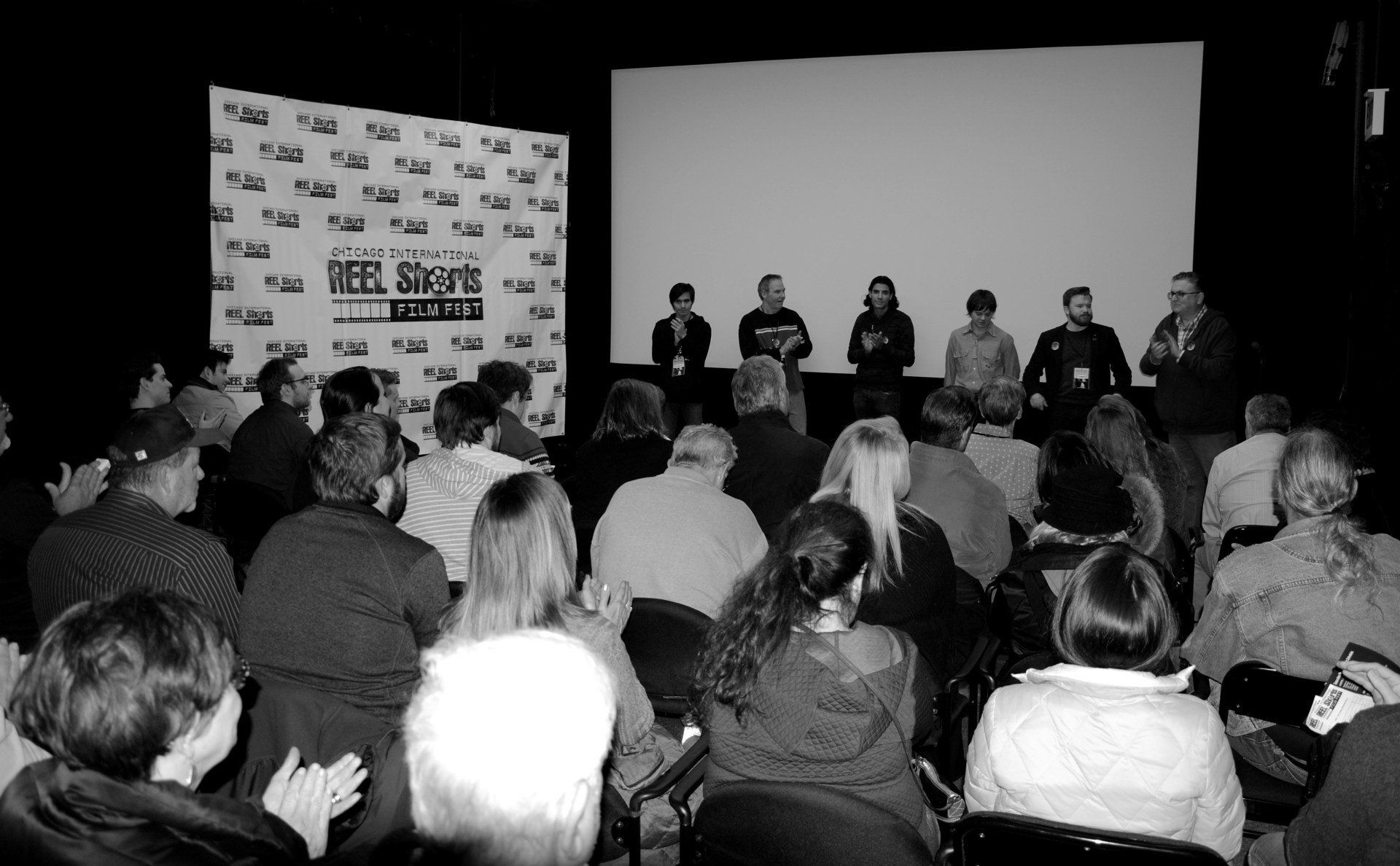 Panel discussion with speakers on stage, audience in seats, event backdrop.