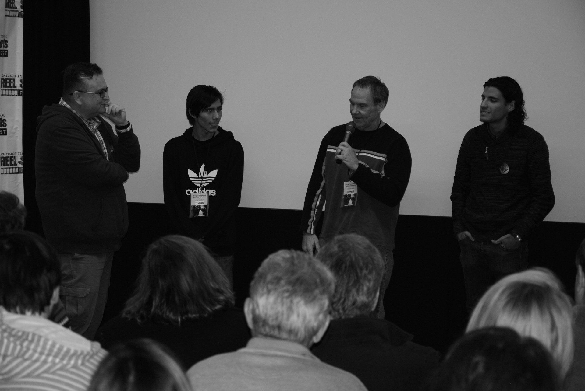Panel discussion: four people on a stage, speaking to an audience in a theater.