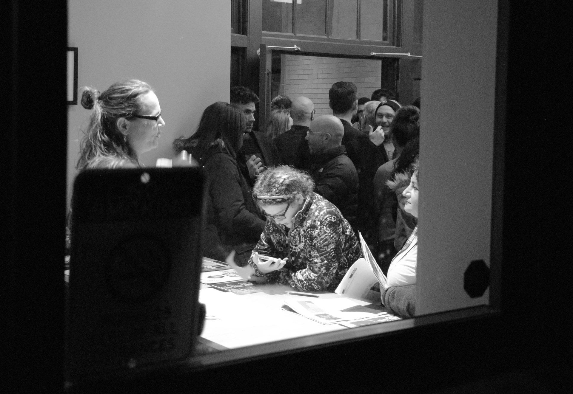 A black and white photo of a group of people standing around a table.