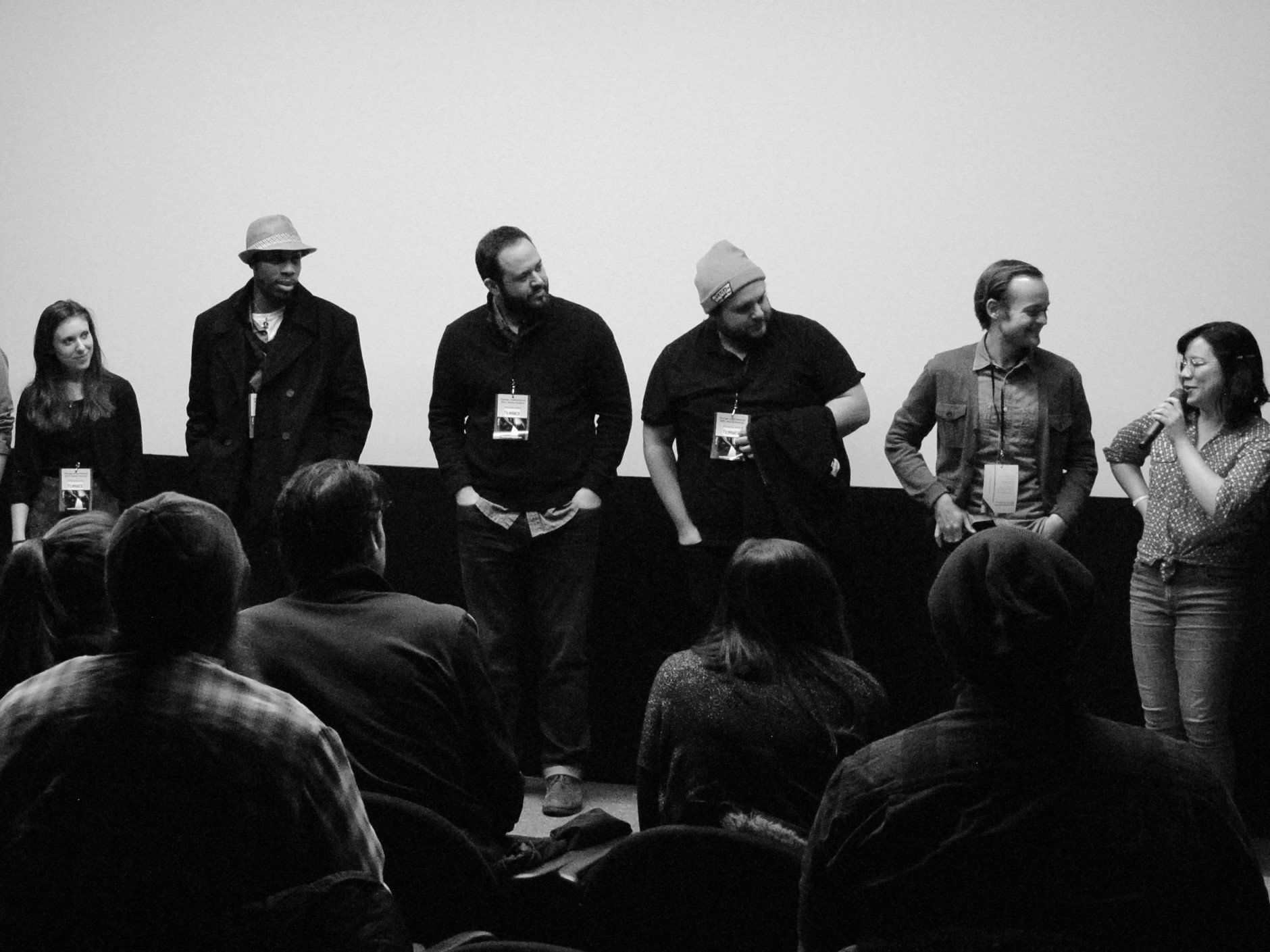 Panel of people on stage, facing an audience. Black and white photo.