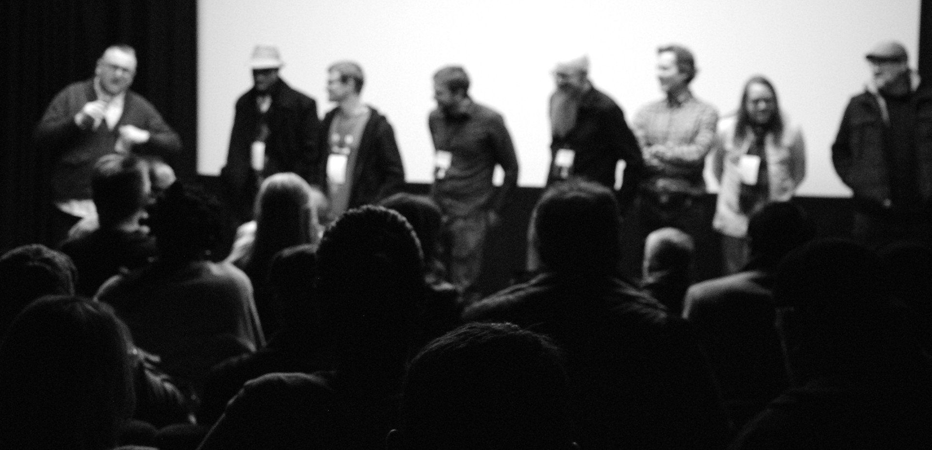 Panel of people on a stage in front of an audience; black and white photo.