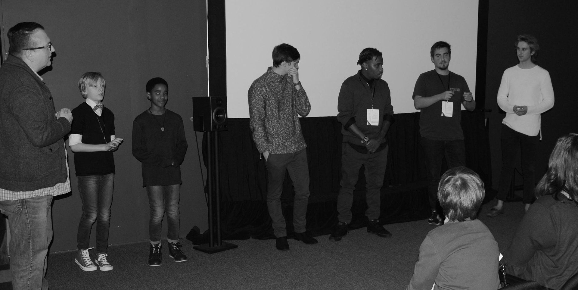 A panel of speakers on stage in front of a screen; audience in the foreground.