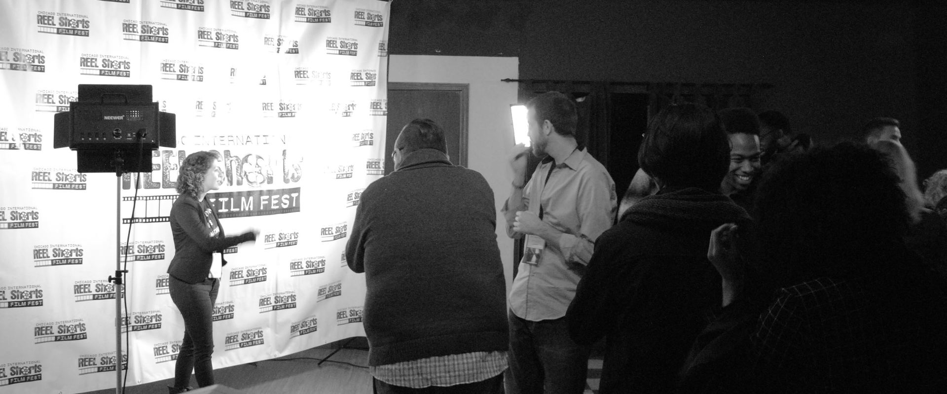 People at an event, likely a film festival, in front of a step-and-repeat backdrop.