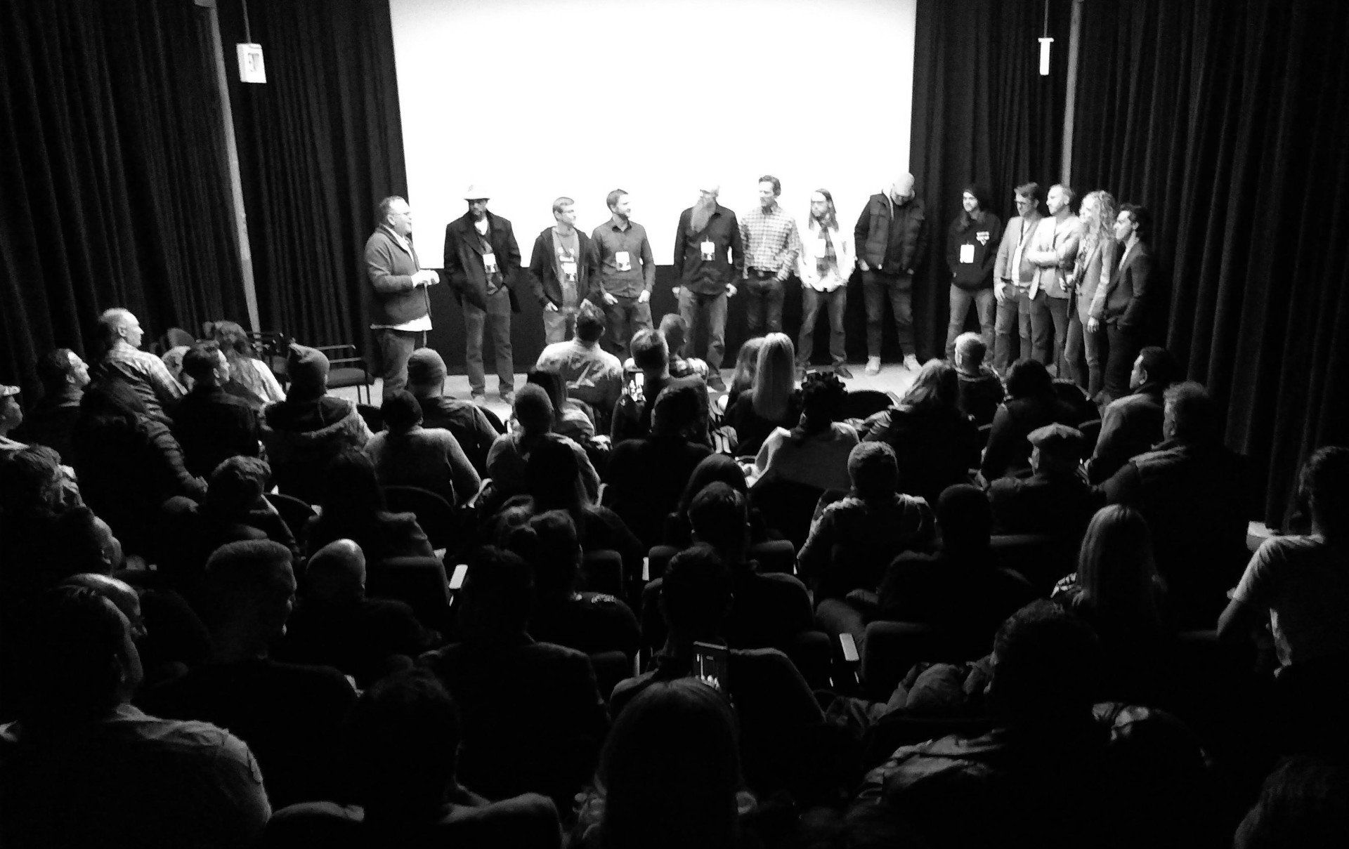 Audience watching a group on stage in a darkened theater.