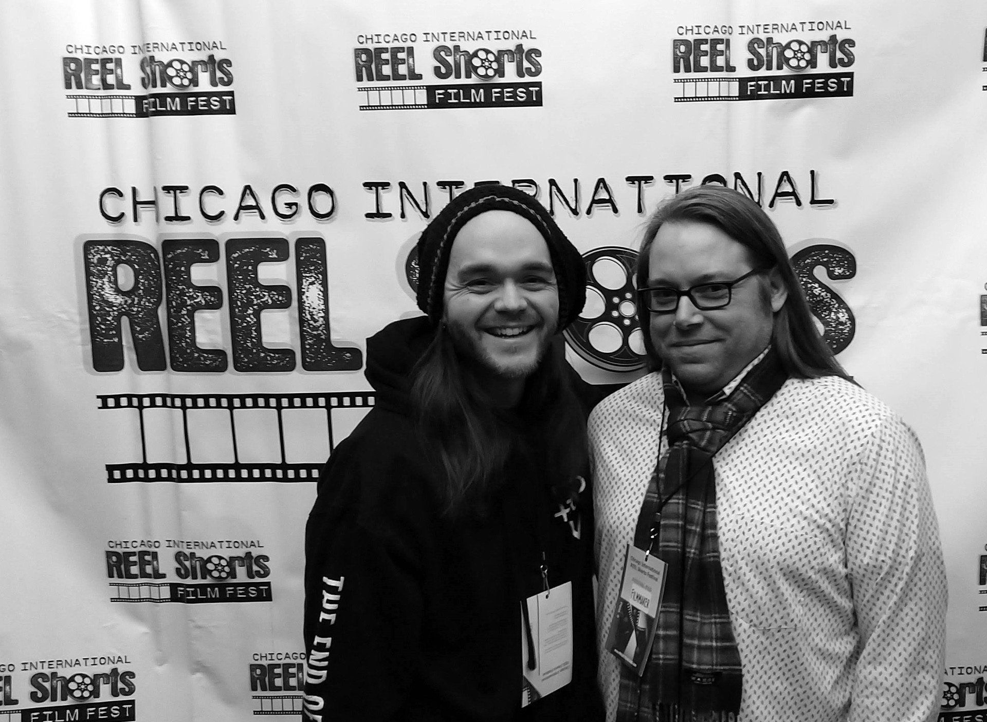 Two men smiling in front of a 