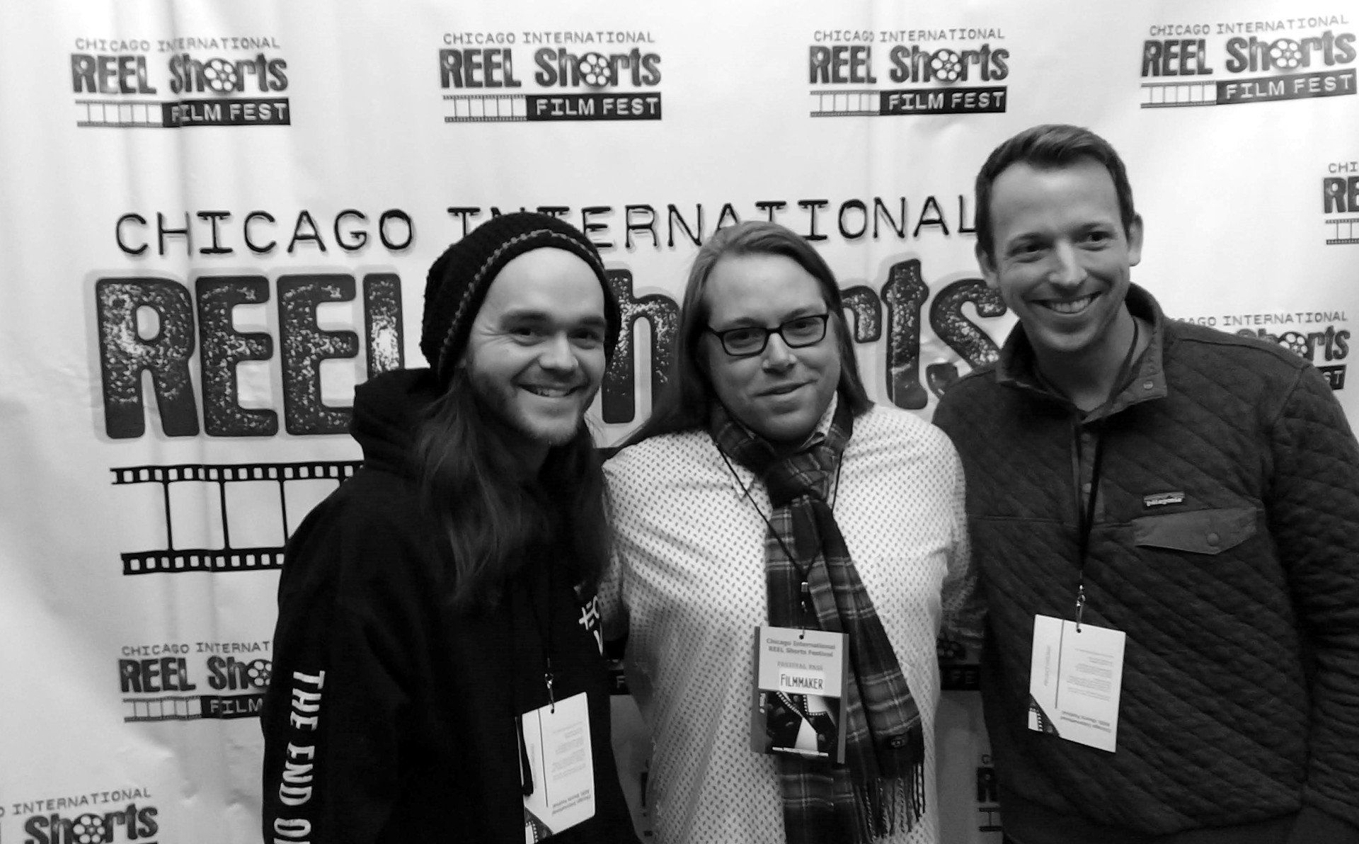 Three people smiling in front of a 