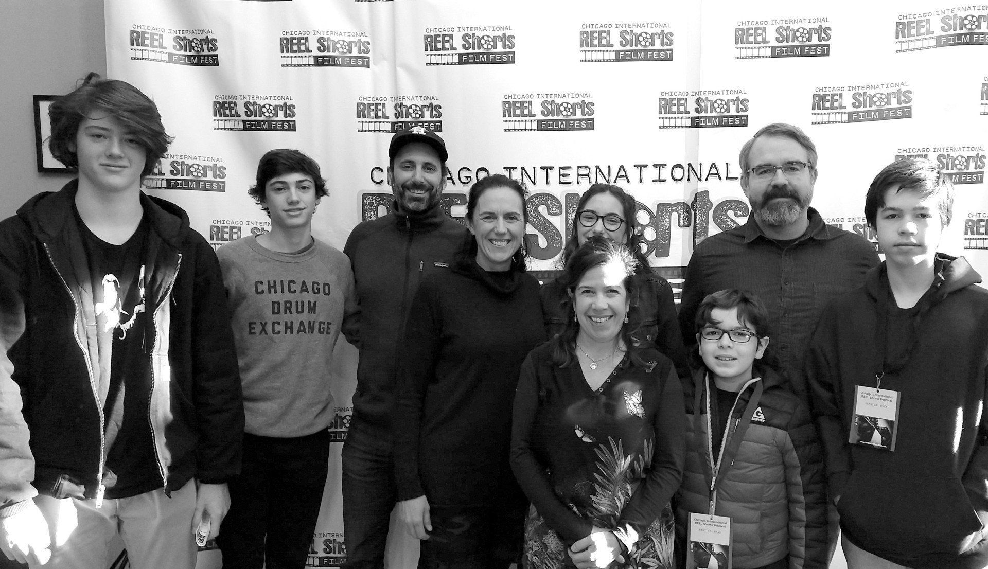 Group of people posing in front of a banner at the Chicago International Reel Shorts Film Festival.