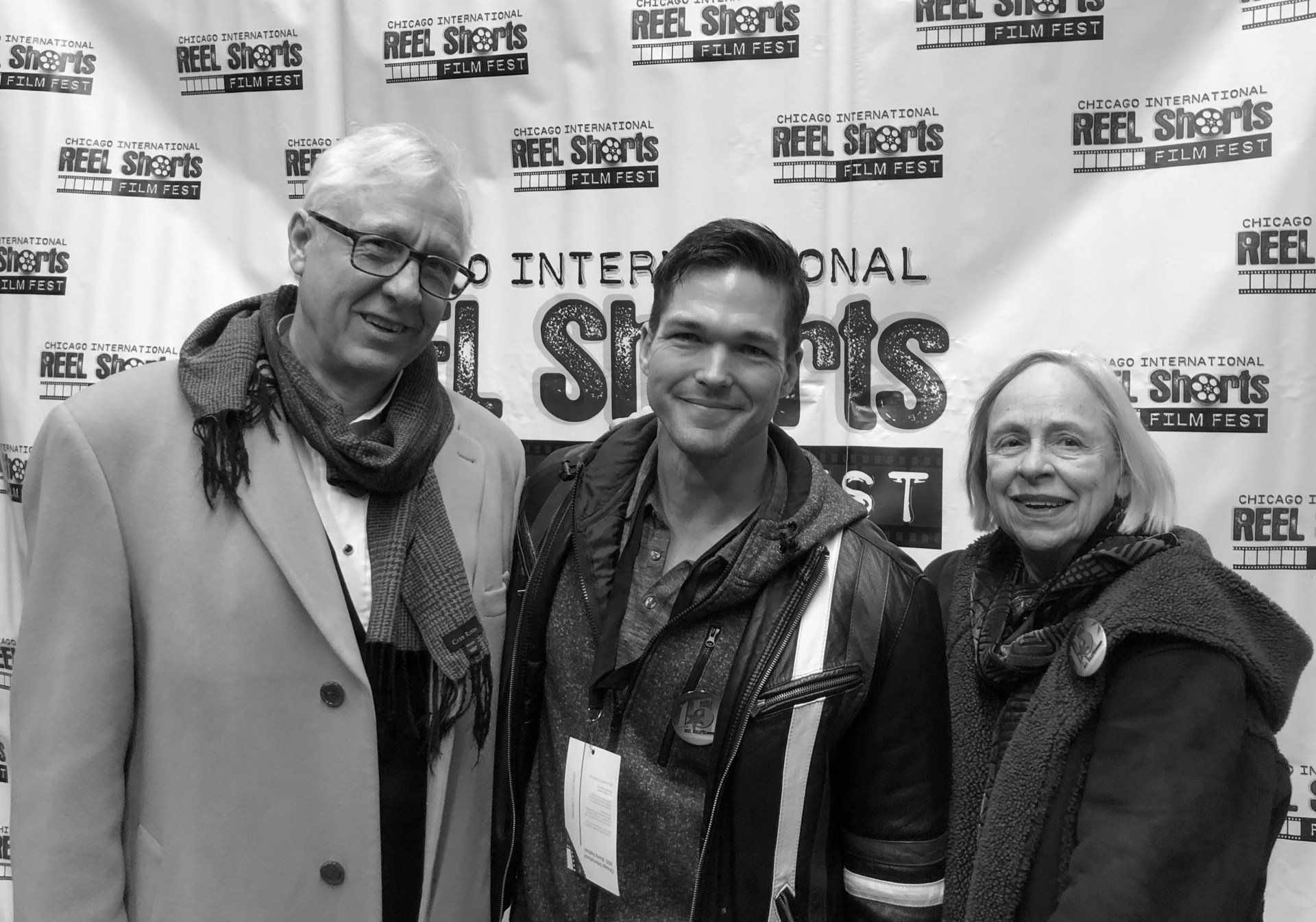 Three people pose in front of a 