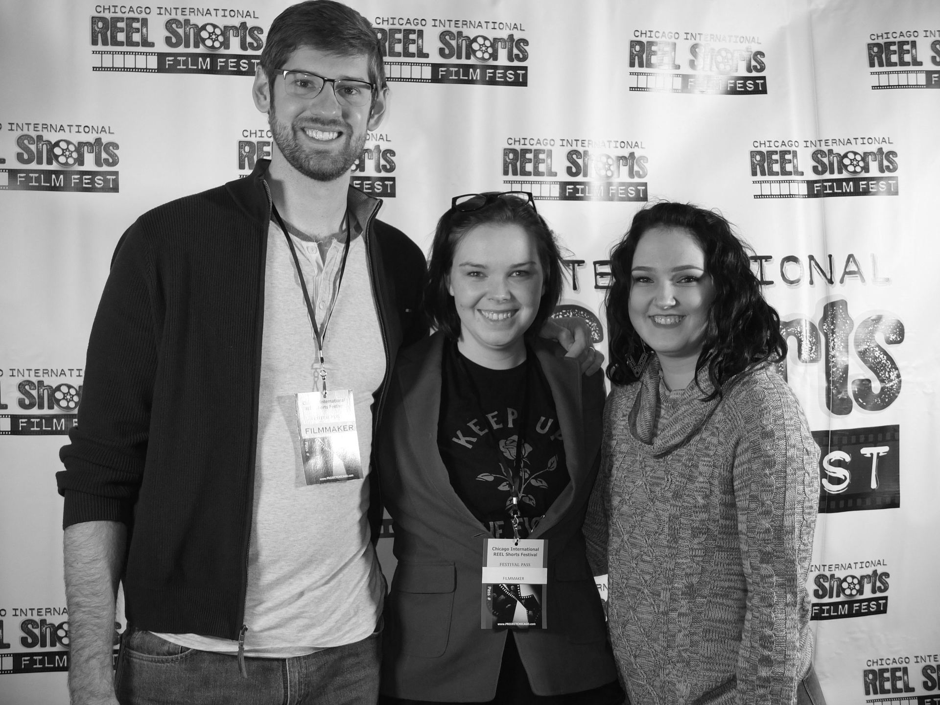 Three people smiling, posing in front of a 
