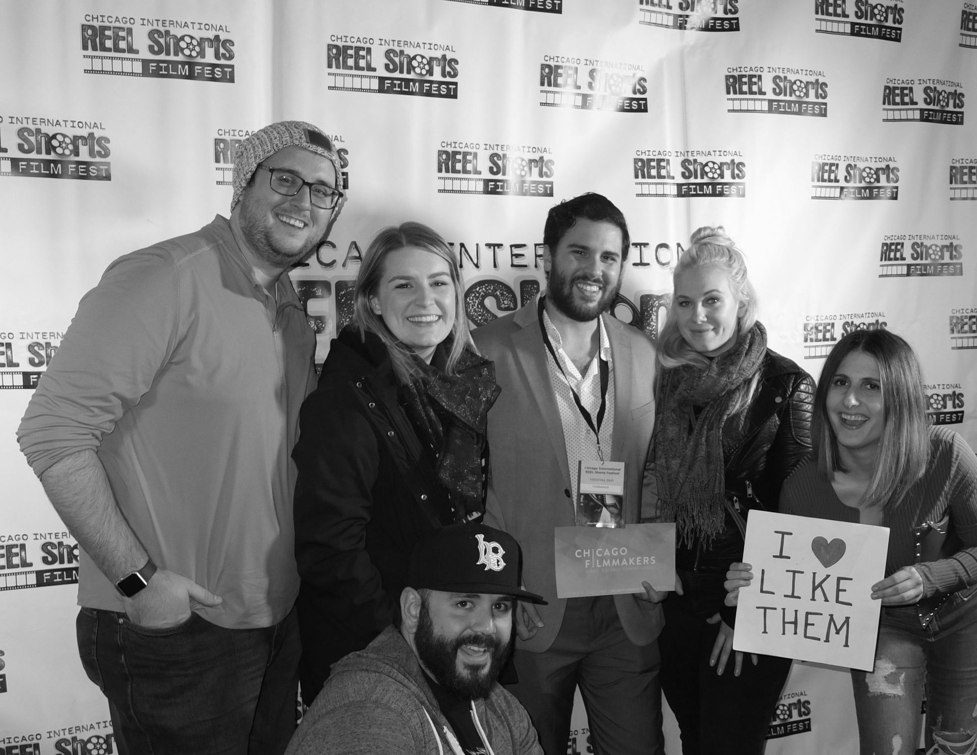 Group of people at a film festival posing for a photo. One holds a sign: 