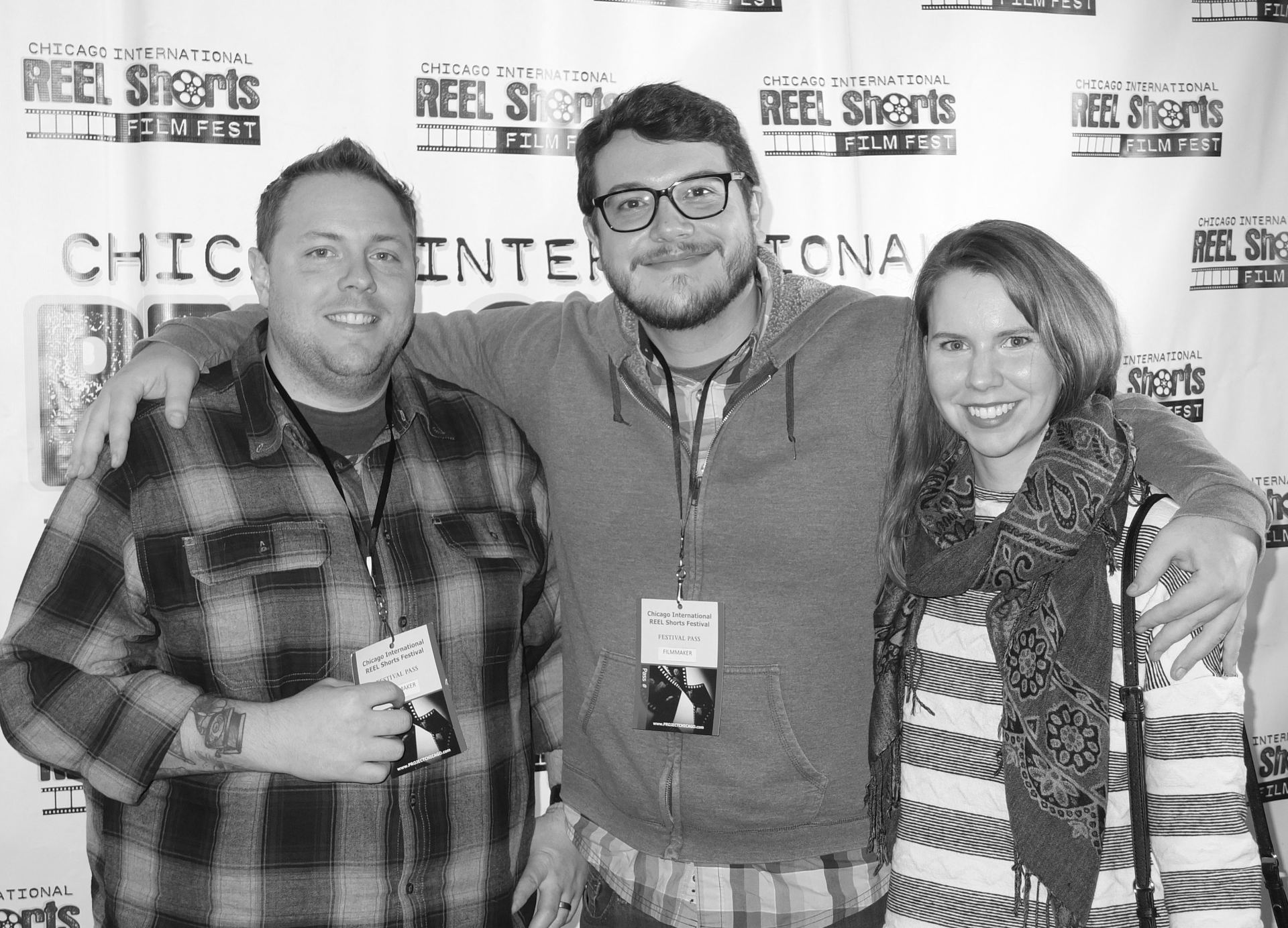 Three people at a film festival: man with plaid shirt, man with glasses and beard, woman with scarf, posing.