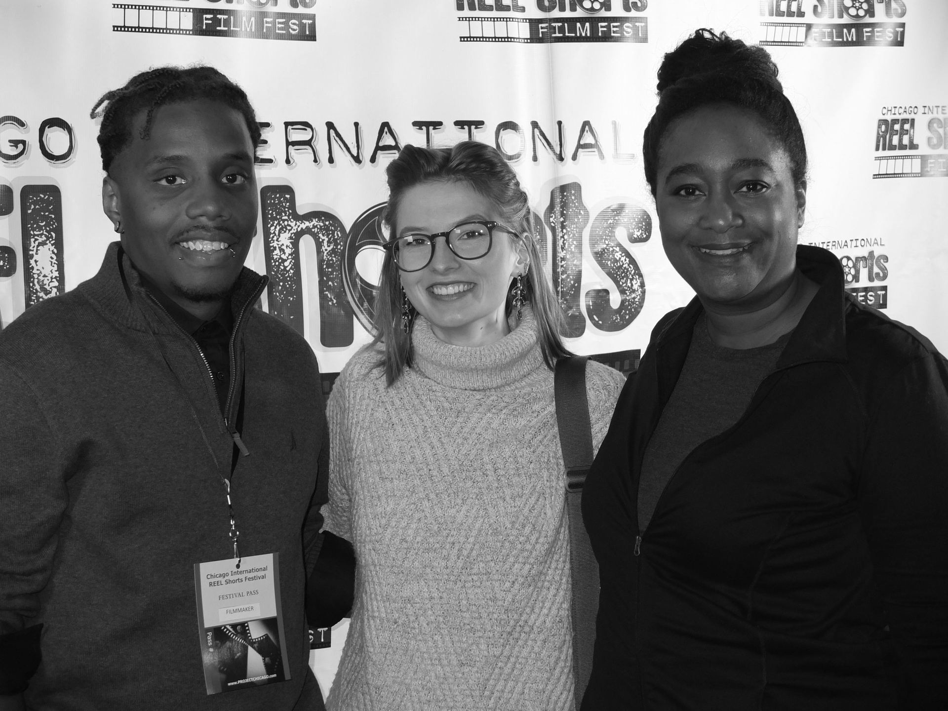 Three people smiling at an event, in front of a banner: Chicago International Shorts Film Festival.